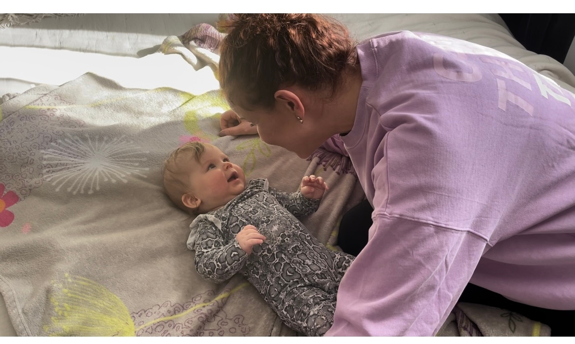 A person interacting with a smiling baby, symbolizing communication and care